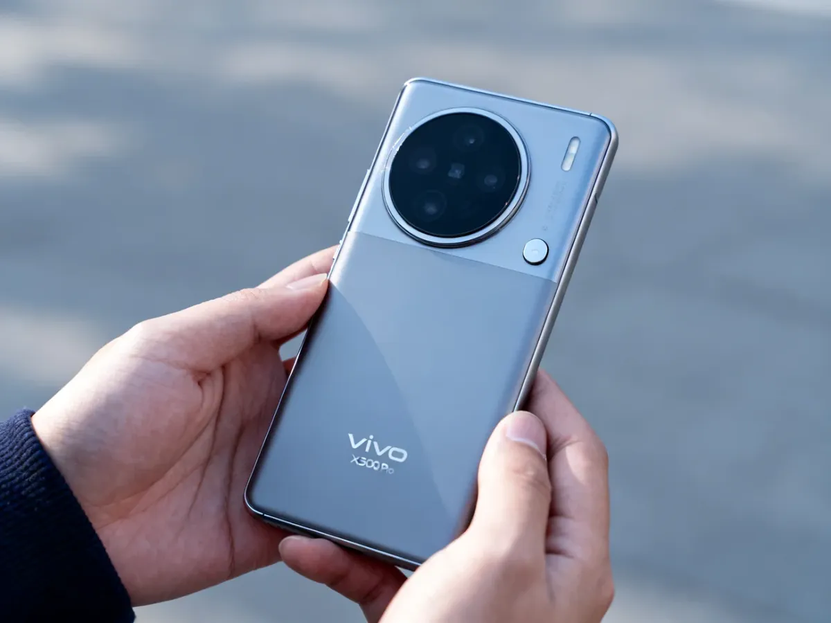 Vivo X300 Pro trzymany w dłoniach fotografa, z widoczną płaską obudową i dużą okrągłą wyspą aparatów